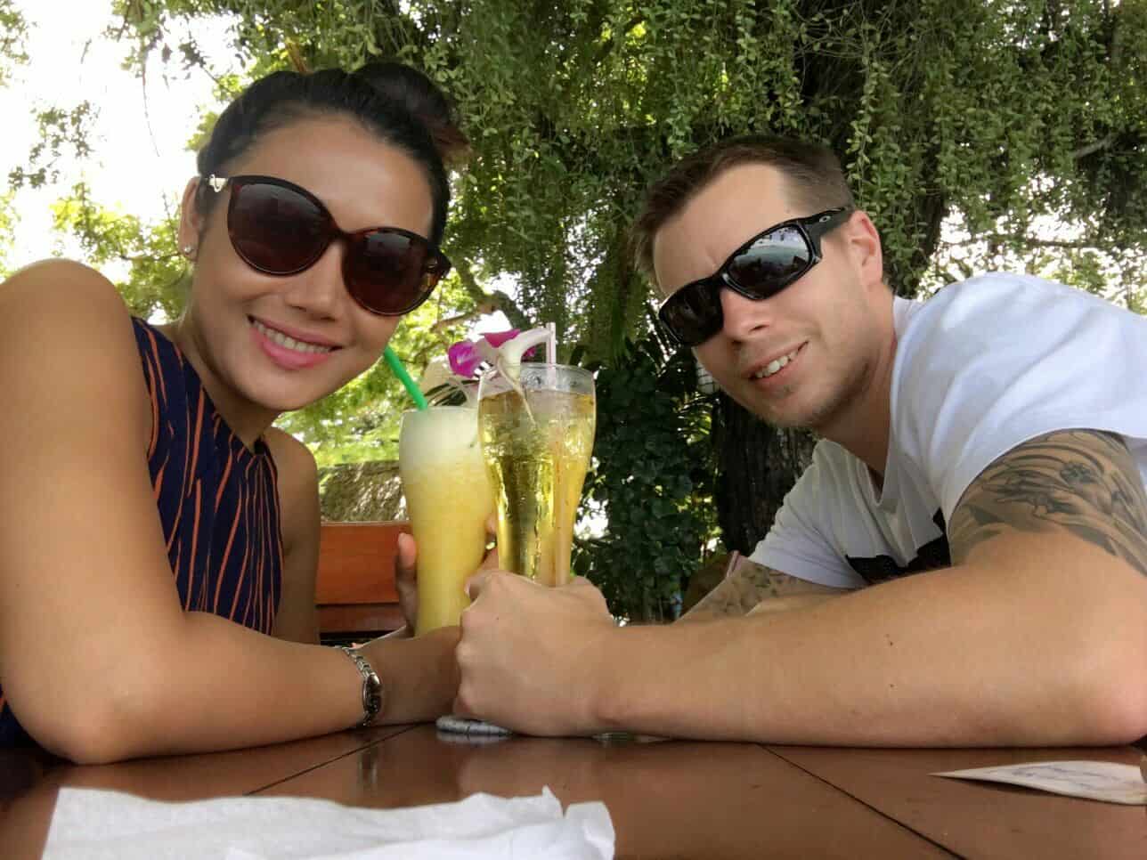 A couple enjoying a sunny day outdoors on a phoenix patio with a refreshing drink at a table. Phoenix Patios, Cottages and Granny Flats in Perth