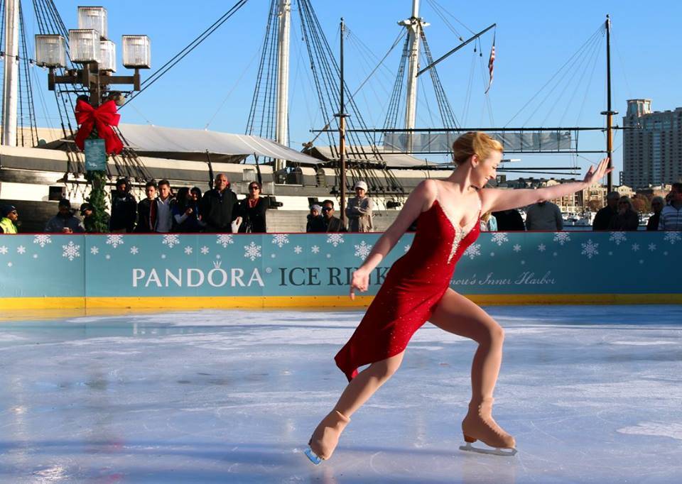 A woman in a red dress skating on an ice rink.